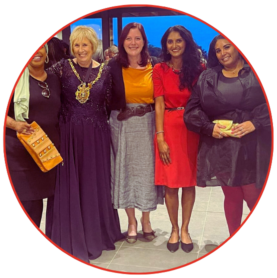 A diverse group of women standing together in a circle, engaged in conversation and sharing smiles.