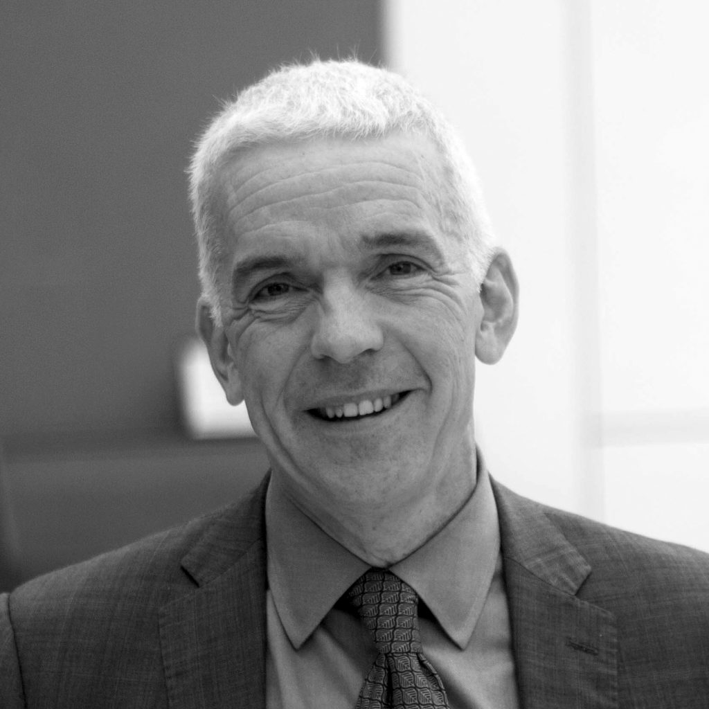 A black and white portrait of a man in a tailored suit, reflecting a timeless and professional style.